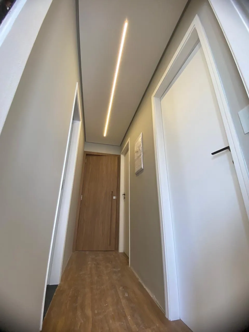 Corredor de residência com pintura branca e rodapés recortados