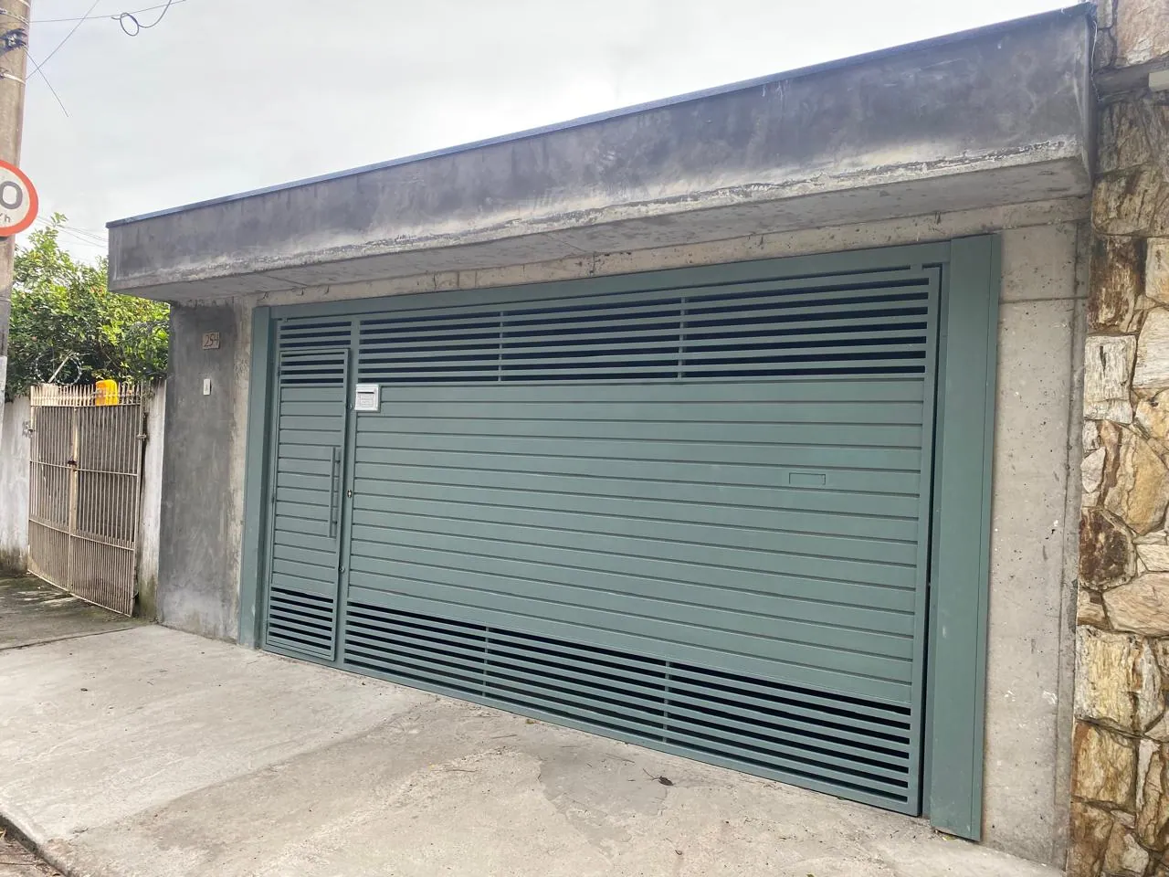Fachada de garagem com pintura verde e acabamento uniforme