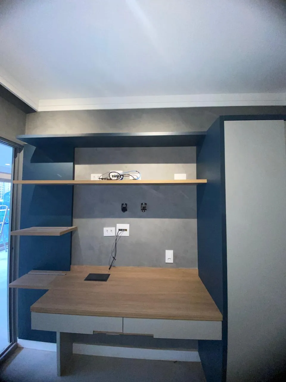 Home office com parede azul e recorte perfeito no encontro com o teto